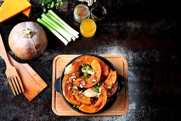 Kürbisstücke in einer kleinen Pfanne mit Gemüse und Samen gebacken. Gebackener Kürbis. Veganes Mittagessen mit würzig gebackenem Kürbis. Nützlicher Herbstsnack. Halloween-Mittagessen.