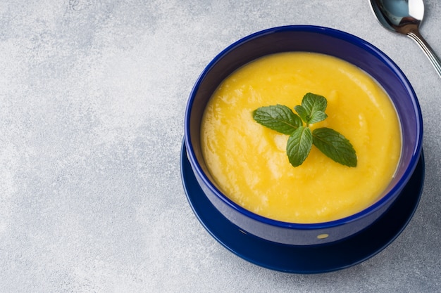 Kürbissuppe auf dem Tisch gestampft mit Gewürzen in einer blauen Platte.