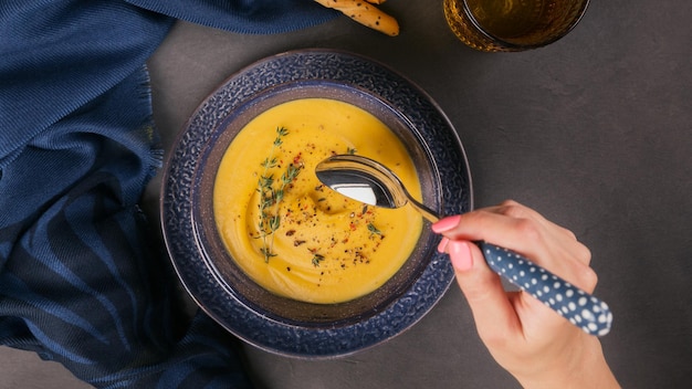 Kürbissuppe in blauer Schüssel mit frischem Kraut