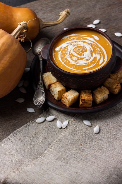 Kürbissuppe mit Sahne und Sesam mit Croutons auf Holzoberfläche