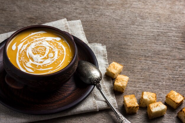 Kürbissuppe mit Sahne und Sesam mit Croutons auf Holzoberfläche