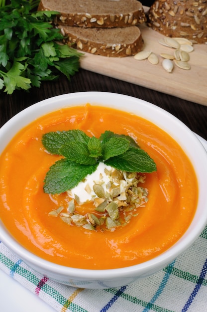 Kürbissuppe mit Sauerrahmsauce, gewürzt mit Kürbiskernen und Minze