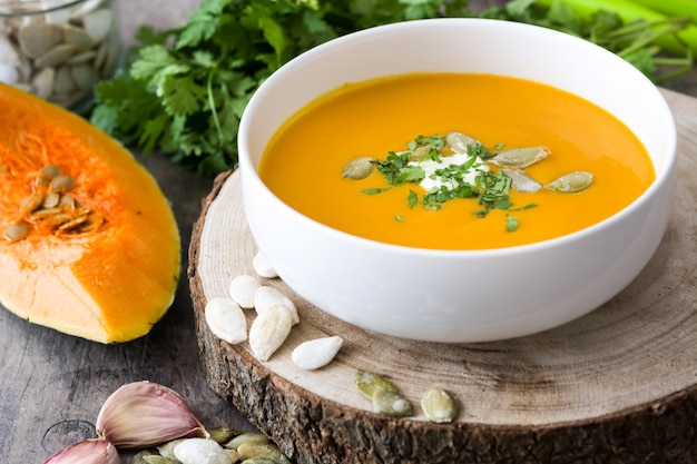 Kürbissuppe und Bestandteile auf einem rustikalen Holztisch