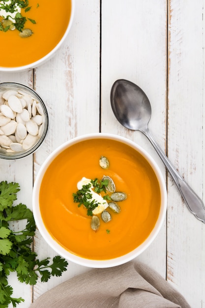 Kürbissuppe und Bestandteile auf weißem hölzernem Hintergrund.