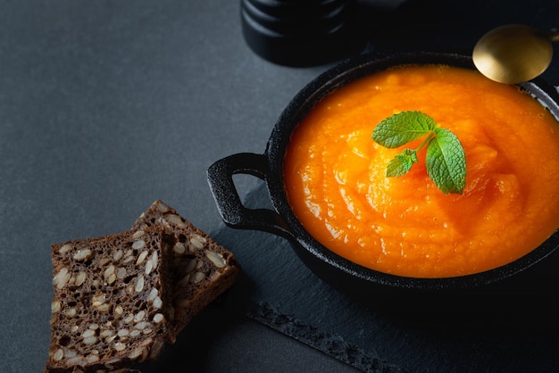 Kürbissuppe und Roggenbrot auf grauem Tisch