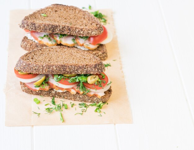 Kürzlich gemachtes Schinkensandwich auf einem weißen Holztisch.