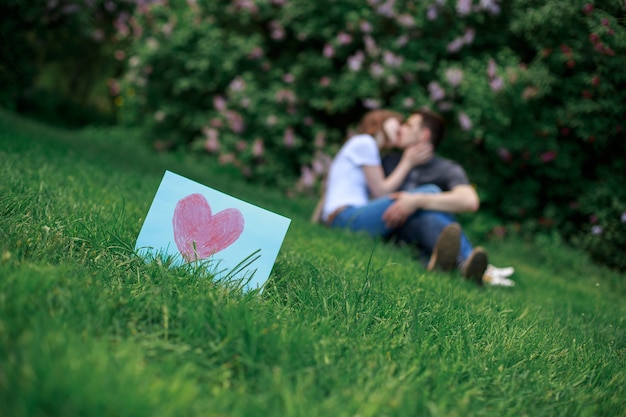 Foto küssen paar in der liebe und grußkarte für valentinstag. liebesgeschichte im freien im grünen frühlingspark