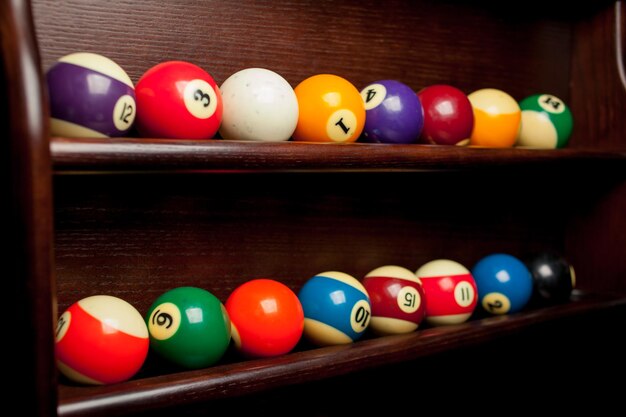 Kugeln für Poolbillard im Regal, Billardkugeln für amerikanisches Billard, Kugeln für russisches Billard, farbige oder weiße Kugeln für Billard auf Holzuntergrund. Nahaufnahmefoto. Weicher Fokus.