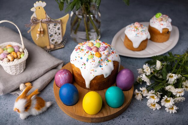 Foto kulich de páscoa com frutas confitadas em esmalte branco com salpicaduras coloridas e ovos pintados pastelaria tradicional de páscua feriado de pásqua foco seletivo de close-up