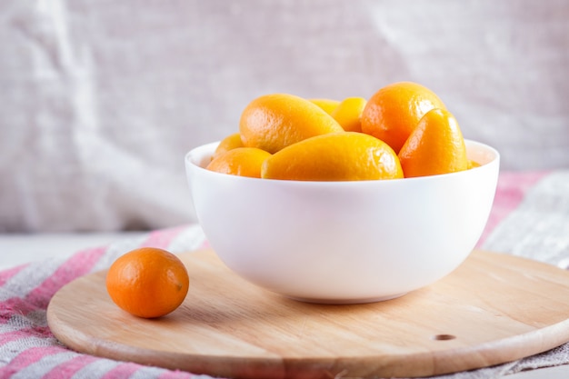 Kumquats en un plato blanco en una tabla de cocina de madera