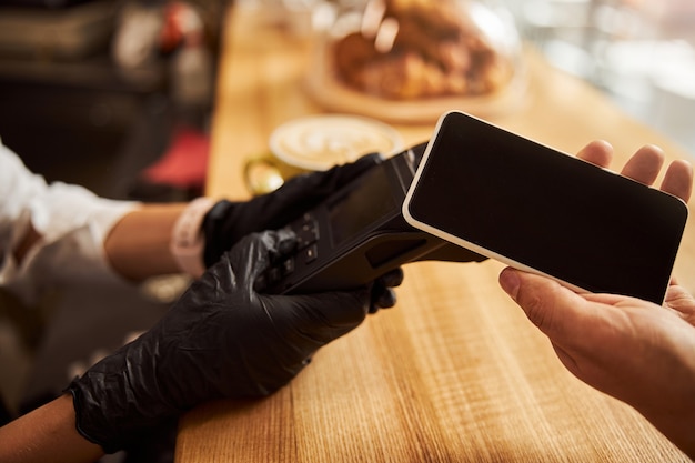 Kunde in der Nähe des elektronischen Zahlungsautomaten im modernen Stadtcafé