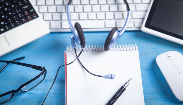 Kundendienst-Headset-Computertastatur und Geschäftsobjekte auf blauem Hintergrund