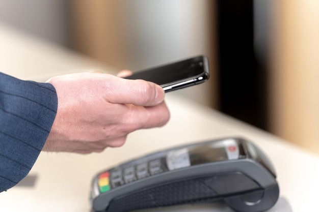 Kundenhand, die Smartphone hält, um im Ladengeschäft einzukaufen Konzept Kontaktlose Zahlungssysteme, die Geld per Technologiegerät ausgeben