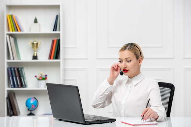 Kundenservice süßes blondes Mädchen Bürohemd mit Headset und Computer im Gespräch mit einem Kunden