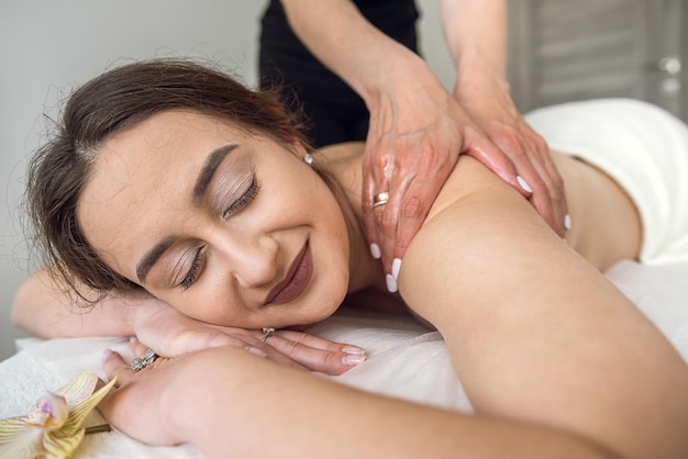 Kundin erhält Physiotherapie von Masseurin auf Schulter und Rücken im Spa-Schönheitssalon