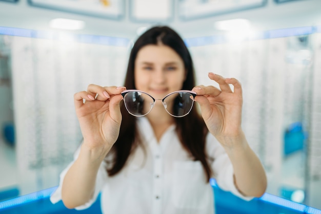 Kundin hält Brille in der Hand, Optikladen