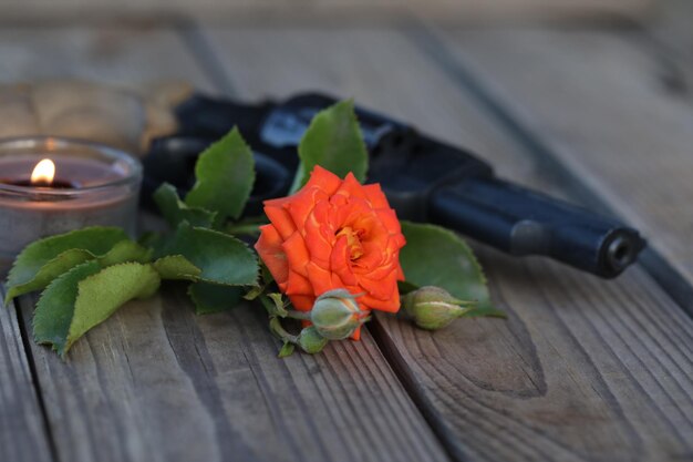 Kunstfoto. Vintage-Stillleben mit Gewehr und Rose auf Holzhintergrund