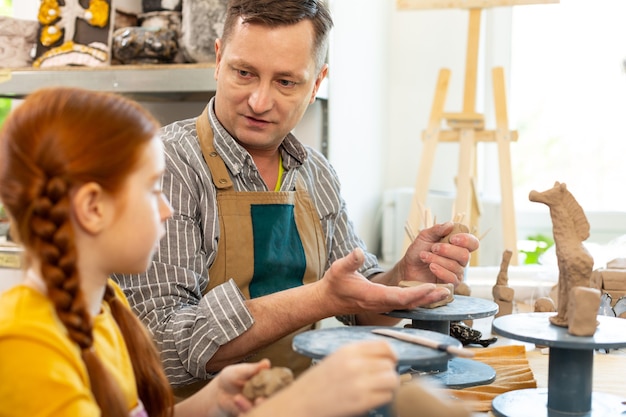 Kunstlehrer mit Schürze im Gespräch mit seinem kleinen Schüler