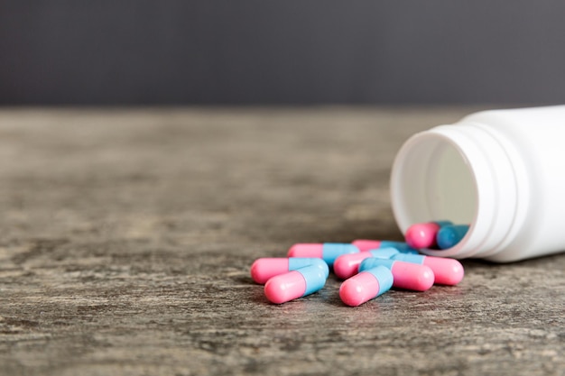 Kunststoff-Medizinflasche mit Kapseln von Pillen auf farbigem Hintergrund Online-Apotheke Schmerzmittel und Antibiotika-Resistenzkonzept Pharmazeutische Industrie
