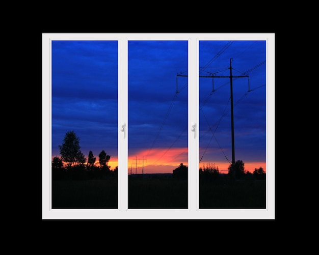 Kunststofffenster mit Blick auf den wunderschönen purpurroten Sonnenuntergang. Blick vom Fenster zu Hause bei Sonnenuntergang. Purpurfarbener Sonnenuntergang vor dem Fenster. Abends draußen