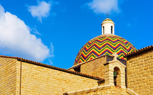 Kuppel der Kirche Chiesa di San Paolo Apostolo in der Altstadt von Olbia auf der Insel Sardinien in Italien. Kathedrale in Sardinien. Blauer Himmel mit weißen Wolken im Hintergrund. Gemischte Medien.