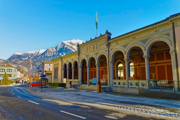 Kurhaus mit Katzenstatue und Bergen. Bad Ragaz ist eine Stadt in St. Gallen in der Schweiz, über den Bündner Alpen. Kur und Erholung ist am Ende des Taminatals