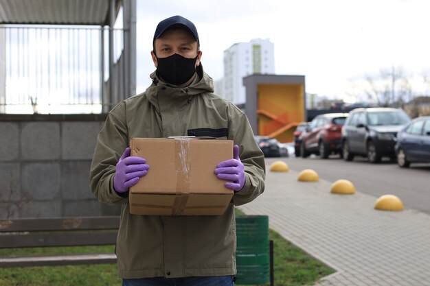 Kurier in Gesichtsmaske und Medizinhandschuhen liefert Paket. Coronavirus und Quarantänekonzept.