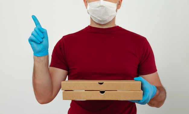 Kurier in medizinischen Handschuhen und Maske hält Pizzaschachteln. Pizza Lieferung während der Quarantäne. Service Quarantäne Pandemie Coronavirus Virus Grippe 2019-ncov Konzept.