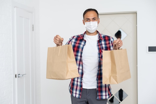 Kurier in Schutzmaske liefert Essen zum Mitnehmen. Lieferservice unter Quarantäne, Krankheitsausbruch, Coronavirus Covid-19-Pandemiebedingungen.