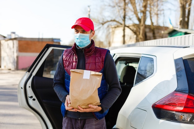 Kurier in Schutzmaske und medizinischen Handschuhen liefert Essen zum Mitnehmen. Lieferservice unter Quarantäne, Krankheitsausbruch, Coronavirus Covid-19-Pandemiebedingungen.