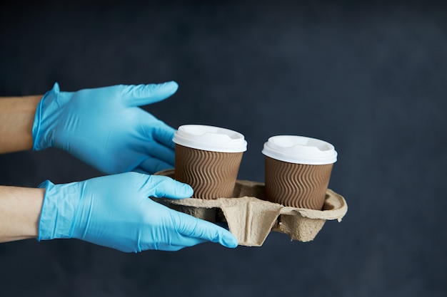 Kurier in Schutzmaske und medizinischen Handschuhen liefert Essen zum Mitnehmen und Kaffee. Lieferservice unter Quarantäne, Krankheitsausbruch, Coronavirus-Covid-19-Pandemie.