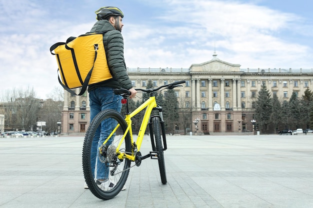 Kurier mit Thermotasche und Fahrrad auf der Stadtstraße Lieferservice für Lebensmittel