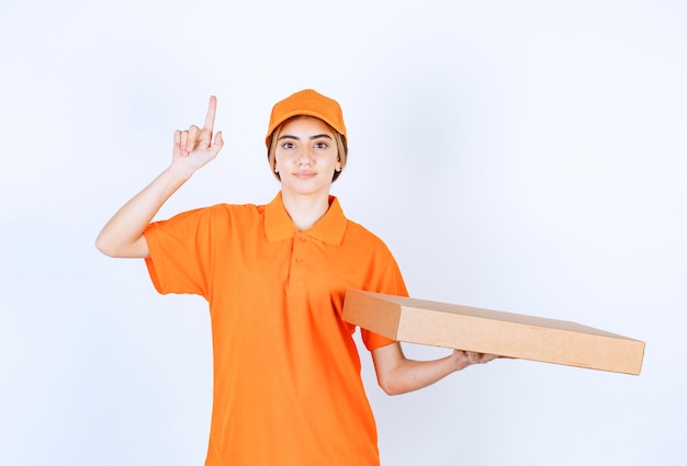 Kurierin in orangefarbener Uniform, die einen Karton liefert