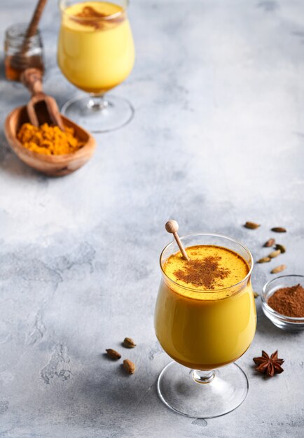 Foto kurkuma-goldener milchlatte mit zimtstangen und honig. gesundes ayurvedisches getränk. trendiges asiatisches natürliches detox-getränk mit gewürzen für veganer. platz kopieren.