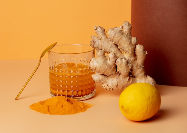 Kurkuma, Honig, Zitrone und Ingwer neben einem Glas auf einem Papier