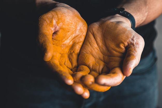 Kurkuma in der Hand mit schwarzem Hintergrund. Medizin. Nahrungsergänzungsmittel.