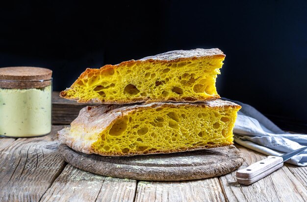 Kurkumabrot auf Serviettenmessermehl und Kurkumapulver auf Holztisch mit dunklem Hintergrund