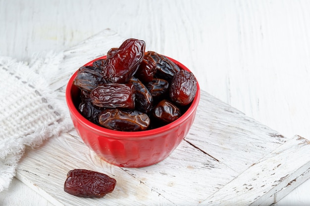 Kurma o frutos secos de palma dulce en un recipiente sobre fondo blanco.