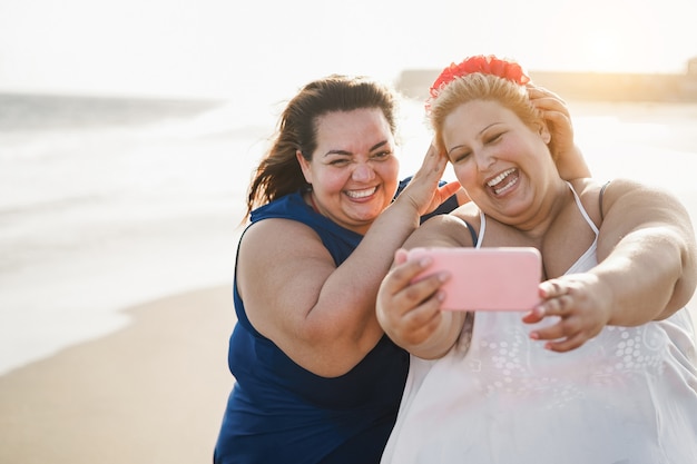 Kurvige Freundinnen, die während der Sommerferien Selfie am Strand machen - Weicher Fokus auf das rechte Gesicht der Frau