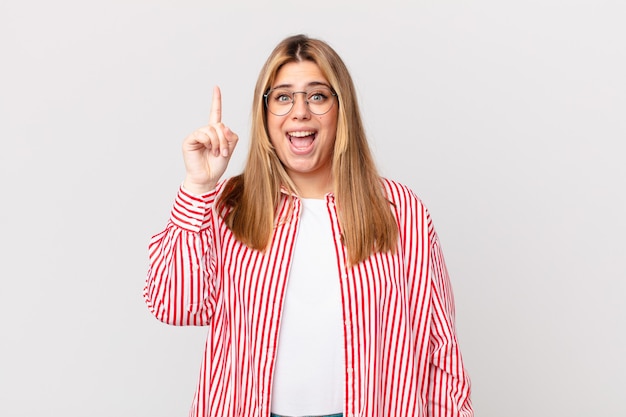 Kurvige hübsche blonde Frau, die sich wie ein glückliches und aufgeregtes Genie fühlt, nachdem sie eine Idee realisiert hat