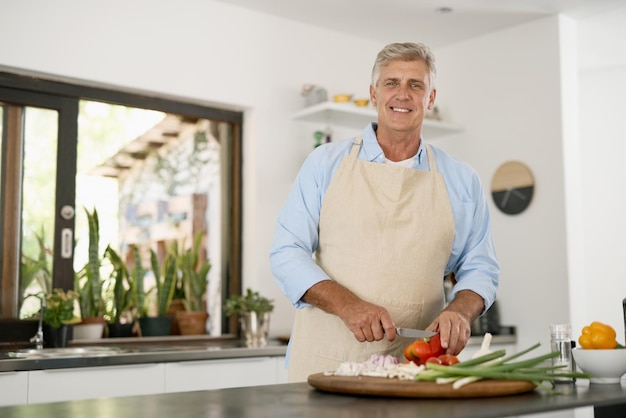 Kurz davor, etwas Gesundes und Leckeres zuzubereiten Zugeschnittenes Porträt eines reifen Mannes, der zu Hause eine gesunde Mahlzeit kocht