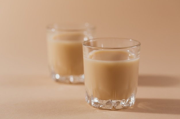 Kurze Gläser Irish Cream Liquor oder Kaffeelikör auf hellbeigem Hintergrund