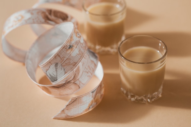 Kurze Gläser Irish Cream Liquor oder Kaffeelikör mit Band auf hellbeigem Hintergrund