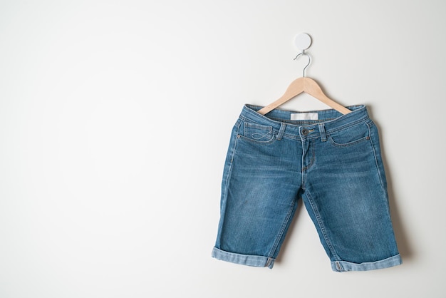 kurze Hosen Jeans mit Holzbügel an der Wand hängen