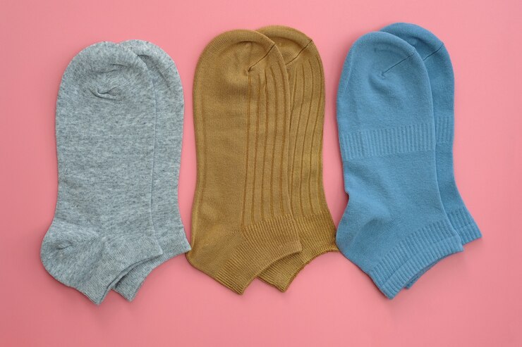 Kurze Socken der grauen, braunen und blauen Farbe auf einem rosa Hintergrund