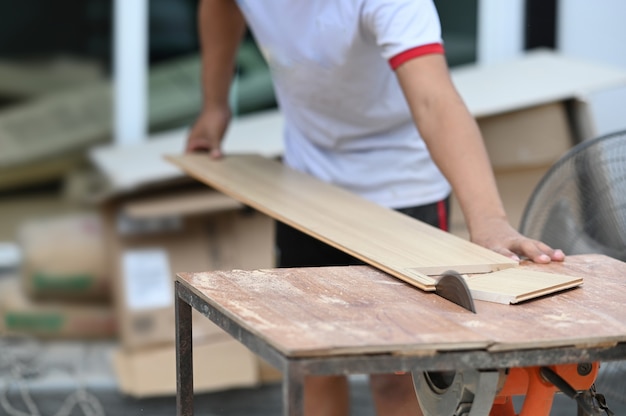 Kurzer Schuss eines Zimmermanns, der in seiner Holzwerkstatt ein Stück Holz schneidet.