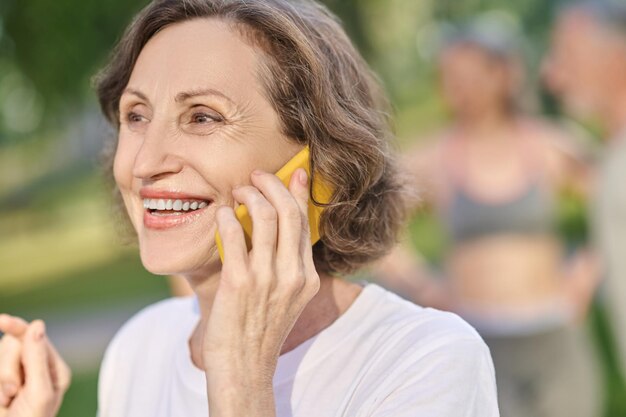 Kurzhaarige Frau in einem weißen T-Shirt mit einem Smartphone