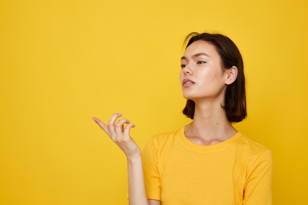 Kurzhaariger Brunette im gelben T-Shirt, das gelben Hintergrund der Mode aufwirft