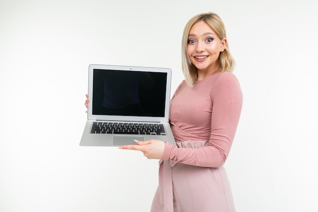 Kurzhaariges Mädchen mit weißen Haaren zeigt einen Laptop-Bildschirm mit einem leeren Rohling auf einem weißen Studiohintergrund