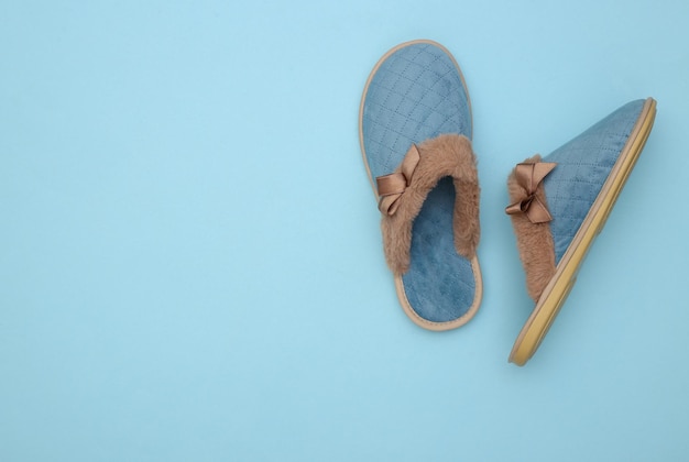 Kuschelige Damen-Schlafpantoffeln auf blauem Pastellhintergrund. Ansicht von oben